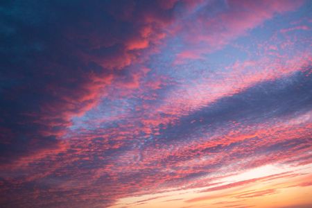 Colorful orange and blue dramatic sky with clouds and shining sunの写真素材