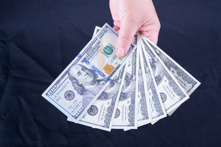 Woman's hand holding money isolated on black backgroundの写真素材