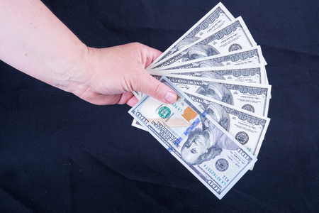 Woman's hand holding money isolated on black backgroundの写真素材