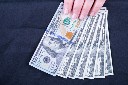 Woman's hand holding money isolated on black backgroundの写真素材
