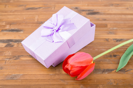 red tulips with gift on wood backgroundの写真素材