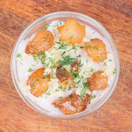 A transparent bowl with lard and grilled cracklings with a crispy crust on a wooden stand. Sprinkled with dillの写真素材