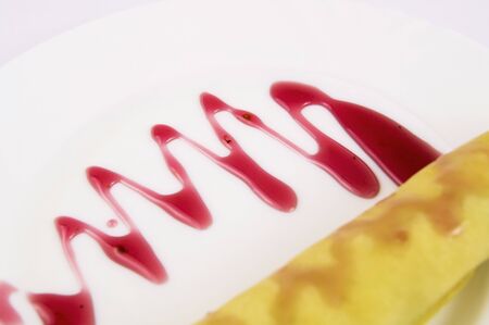 Pancake in a white plate with raspberry jam on a white background