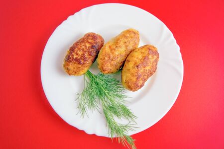 Cutlets from fish on a white plate with greens