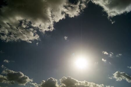 Gray clouds and the sun against the blue skyの写真素材