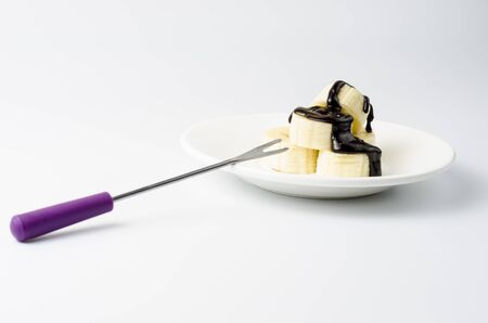 Sliced ââbananas in chocolate icing on a white saucerの写真素材