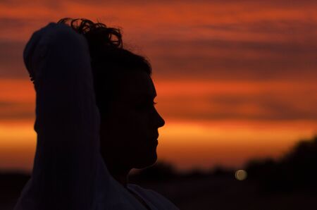 Woman on a background of colorful beautiful sunsetの写真素材
