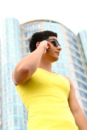 Attractive fit young businessman using a cell phone in front of a modern office buildingの写真素材