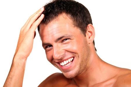 Closeup of a happy young man looking at camera and touching his hair