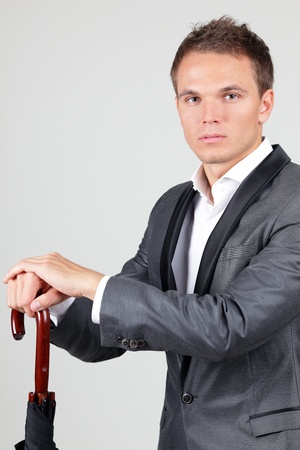 Image of successful businessman in elegant suit with folded umbrellaの写真素材