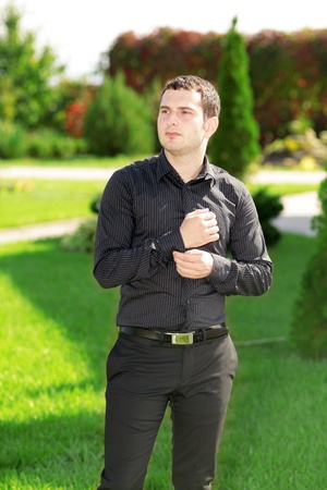 Portrait of young attractive business man standing in the yard in front of his house. Sunny day. の写真素材