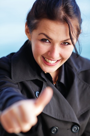 Young happy brunette woman on the beach with thumbs upの写真素材