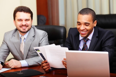 Two businesspartners joking while working with documents in officeの写真素材