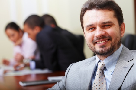 Portrait of a happy senior business man at office with his business team working behindの写真素材