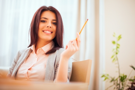 Portrait of a young beautiful confident woman in casual business cloths holding a pencilの写真素材