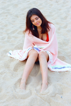 Young beautiful woman wrapped herself with blanket on the beachの写真素材