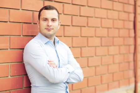 Happy businessman against brick wallの写真素材