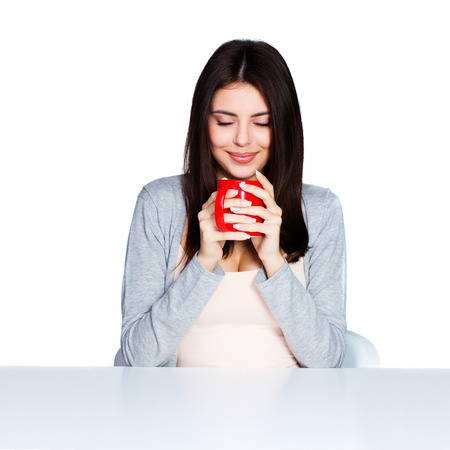 Beautiful young woman holding a cup of her favorite beverage, isolated on whiteの写真素材