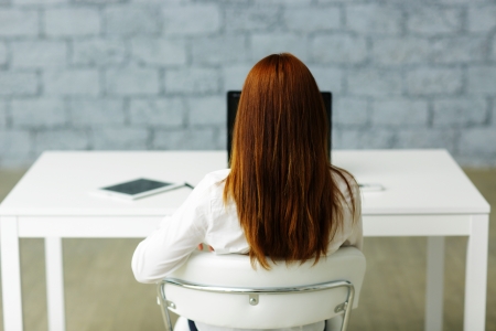 Picture from behind of a businesswoman sitting at her deskの写真素材