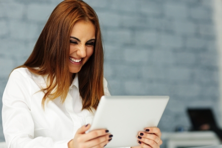 Laughing young businesswoman looking at tablet computer screenの写真素材
