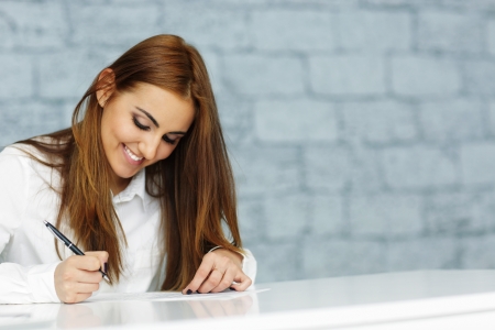 Young happy businesswoman signing document の写真素材