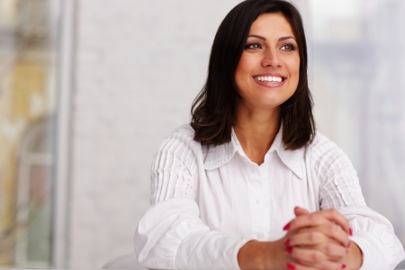 Cheerful confident businesswoman sitting at the table in officeの写真素材