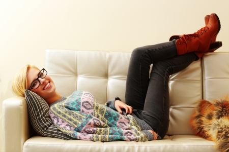 Young happy woman lying on the sofa at homeの写真素材