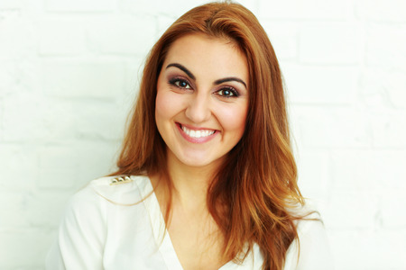 Portrait of a cheerful young woman against white wallの写真素材