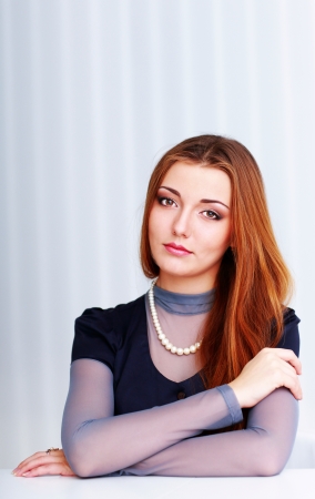 Portrait of a young beautiful pensive woman sitting at the tableの写真素材