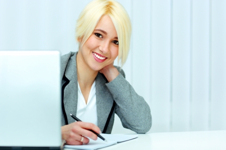 Young cheerful businesswoman signing the document in officeの写真素材