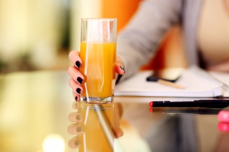Closeup image of a woman hand holding glass of orange juiceの写真素材
