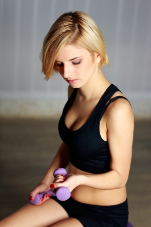 Portrait of a young thoughtful fit woman doing workout with dumbbellの写真素材