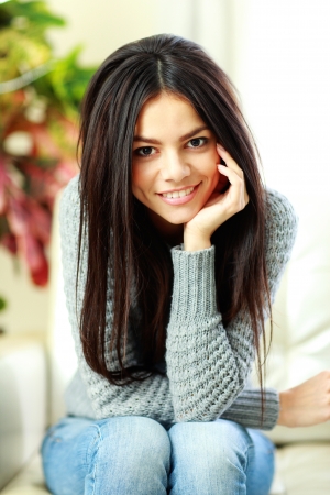 Young beautiful smiling woman sitting on the armchair at homeの写真素材