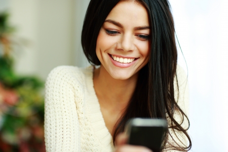 Portrait of a cheerful young woman using her smartphoneの写真素材