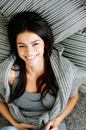 Cheerful woman lying on the floor with pillows. View from aboveの写真素材