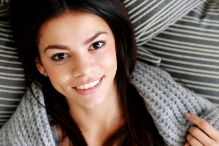 Closeup portrait of a happy woman lying on the floor with pillows. View from aboveの写真素材