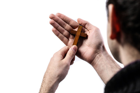 Male hands holding wooden cross on white backgroundの写真素材