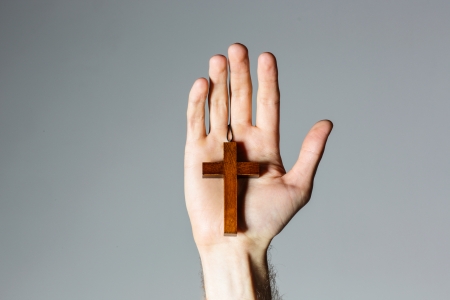 Male hand holding wooden cross on gray backgroundの写真素材