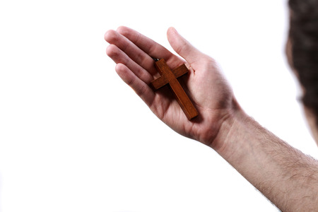 Male hand holding wooden cross on white backgroundの写真素材