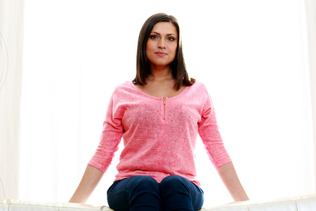 Mature beautiful pensive woman sitting on a white backgroundの写真素材
