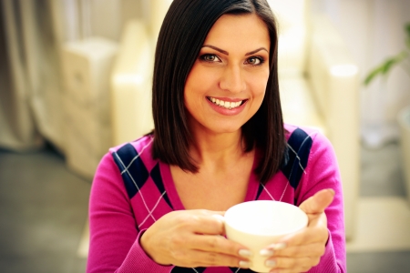Young happy smiling woman holding cup of coffeeの写真素材