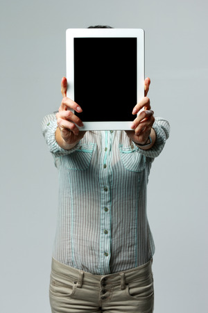 Woman showing tablet computer screen on gray backgroundの写真素材