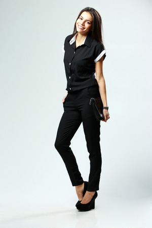 Full-length portrait of a young cheerful woman in style clothes standing on gray の写真素材