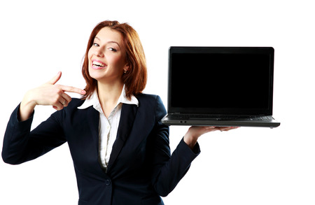 Laughing businesswoman holding laptop and pointing on it isolated on a white backgroundの写真素材