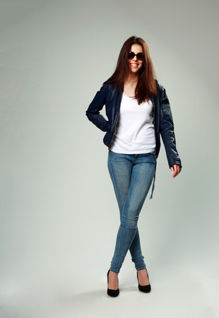 Studio shot of a happy model in leather jacket and sunglasses on gray backgroundの写真素材