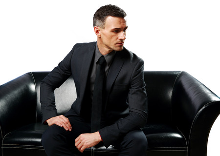 Thoughtful businessman sitting on the sofa isolated on a white backgroundの写真素材