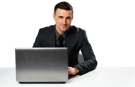 Smiling businessman sitting at the table with laptop isolated on a white backgroundの写真素材