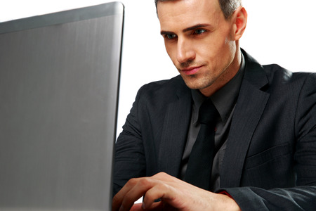 Confident businessman sitting at the table with laptop isolated on a white backgroundの写真素材