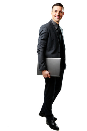 Full-length portrait of a businessman standing with laptop isolated on a white backgroundの写真素材