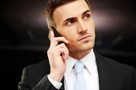Confident businessman talking on the phone at officeの写真素材